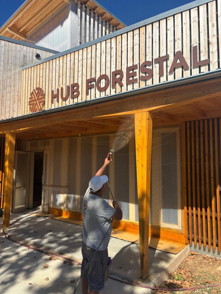 Operario aplicando un tratamiento en la fachada del Hub Forestal